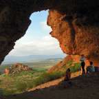 Menschen stehen in einer Höhle mit Blick auf die Landschaft