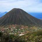 Ein großer Vulkan mit einem kleinen Dorf im Vordergrund