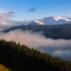 Ein See mit Bergen im Hintergrund und Bäumen im Vordergrund