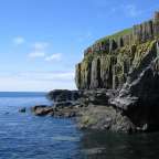Eine felsige Klippe über dem Ozean mit einem blauen Himmel dahinter