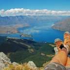Eine Person legt ihre Beine auf einem Felsen mit Blick auf einen See