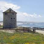 Eine Windmühle steht auf einem Hügel mit Blick auf das Meer