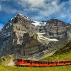 Ein roter Zug fährt in den Bergen
