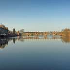 Eine Brücke über einen Fluss mit Gebäuden im Hintergrund
