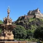 Ein Brunnen in einem Park mit einem Schloss im Hintergrund