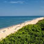 Menschen sitzen und liegen am Strand an einem sonnigen Tag