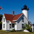 Ein weißes Haus mit einem roten Dach und einem Leuchtturm davor