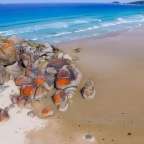 Ein Strand mit großen Felsen und einem blauen Ozean dahinter