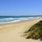 Ein sandiger Strand mit einem blauen Himmel im Hintergrund