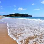 Ein Strand mit einer kleinen Insel im Hintergrund