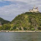 Ein großes Schloss sitzt auf einem Hügel über einem Fluss