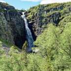 Ein Wasserfall inmitten einer Felswand, umgeben von Bäumen