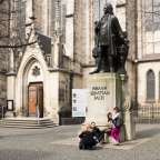 Eine Gruppe von Menschen sitzt vor einer Statue von johann sebastian bach