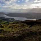 Die Sonne scheint durch die Wolken über einen See