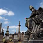 Eine Statue eines Engels hält eine rosa Blume in einem Friedhof