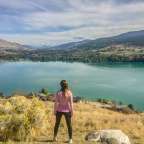 Eine Frau steht auf einem Hügel mit Blick auf einen See