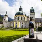 Eine Flasche eisbär sitzt auf einer Bank vor einem großen Gebäude