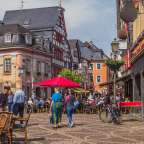 Eine Gruppe von Menschen geht an einem Straßencafé vorbei