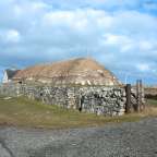 Ein Steingebäude mit Strohdach neben einer Straße