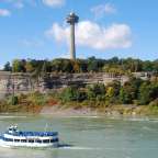 Ein weißes Boot fährt auf einem Fluss mit einem Turm im Hintergrund