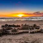 Ein Sandburg auf einem Strand bei Sonnenuntergang