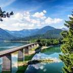 Eine Brücke über einen See mit Bergen im Hintergrund