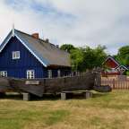 Ein großes Holzboot steht vor einem blauen Haus
