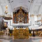 In einer Kirche steht ein goldener Zaun vor einer großen Orgel