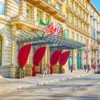 Eine Frau geht vor einem großen Hotel mit roten Vorhängen