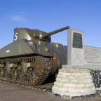 Ein Tank mit der Nummer 5 steht neben einem Denkmal