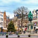 Eine Statue eines Mannes steht inmitten einer Stadt mit vielen Fahrrädern geparkt