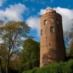 Ein roter Backsteinturm steht inmitten eines Waldes