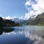 Ein See mit Bergen im Hintergrund und einem blauen Himmel mit Wolken