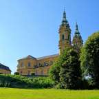 Eine Kirche mit zwei Türmen steht auf einem grünen Hügel