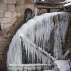 Eiszapfen hängen von einem Wasserrad in der Nähe eines Fensters