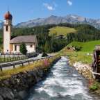Ein Fluss fließt durch ein Dorf mit einer Kirche im Hintergrund
