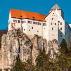 Ein weißes Schloss steht auf einem felsigen Hügel