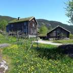 Ein kleines Holzhaus mit grünem Dach steht neben einem größeren Holzhaus