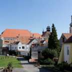 Eine Reihe von Gebäuden mit roten Dächern und einer Kirche im Hintergrund
