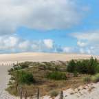 Ein sandiger Weg führt zu einem großen Sanddüne