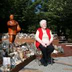 Eine ältere Frau sitzt neben einer Statue eines Mannes