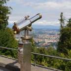 Ein silbernes und bronzefarbenes Fernglas mit einer Stadt im Hintergrund