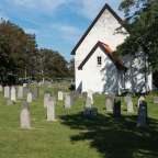 Ein Friedhof mit vielen Grabsteinen und einer Kirche im Hintergrund