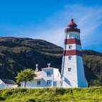 Ein rot-weißer Leuchtturm steht auf einem Hügel