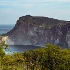 Ein großer Felsen mit Bäumen und einem See dahinter