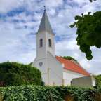 Eine weiße Kirche mit einem roten Dach und einem Kreuz auf dem Turm