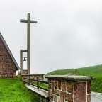 Eine kleine Kirche mit einem Kreuz und einer Glocke davor