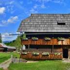 Ein altes Holzhaus mit einem strohdach und Blumenkästen auf dem Balkon
