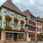 Ein Gebäude mit grünen Fensterläden und roten Blumen darauf