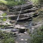 Eine Treppe führt hinunter zu einem Wasserfall im Wald